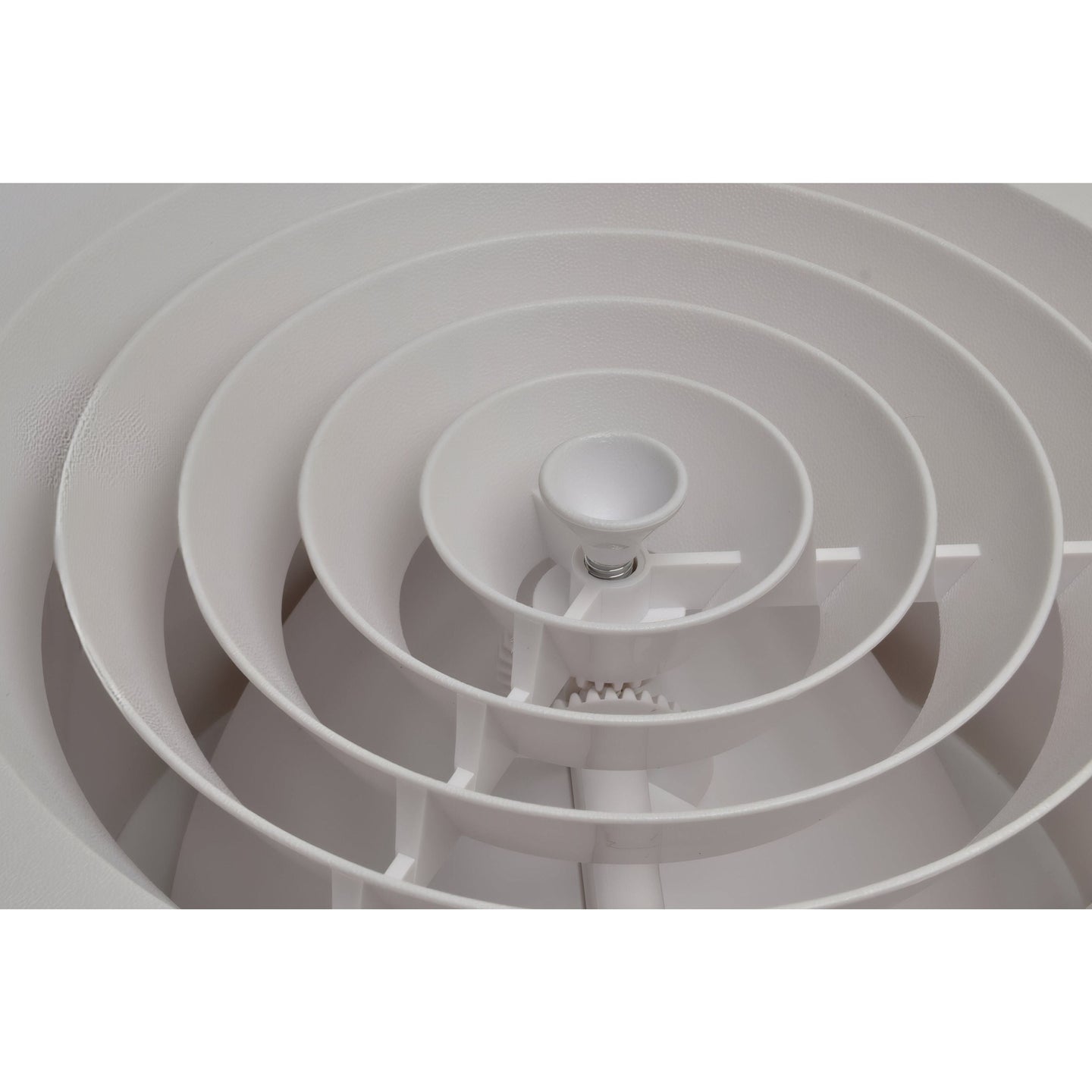 Close-up of a white ceiling vent with concentric circular design

